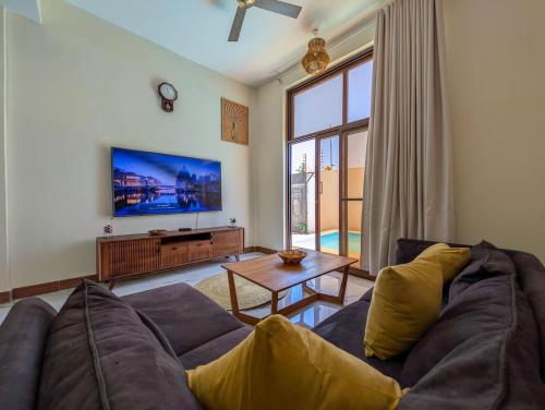 a living room with a couch and a tv at Villa Goli 3BR Private Pool Villa, Paje in Zanzibar City