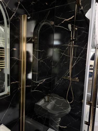 a bathroom with a black marble shower with a sink at Willa Ingeborg in Międzyzdroje