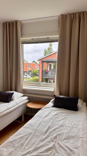 a bedroom with two beds and a large window at Hardangegatan in Östersund