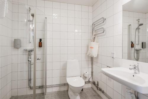 a white bathroom with a toilet and a sink at 2Home Hotel Apartments in Solna