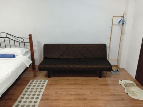 a black couch sitting in a room next to a bed at HG Homestay in Kota Kinabalu