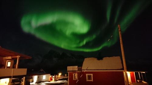 uma aurora no céu sobre um edifício com uma casa em Hammerstad Camping em Svolvær