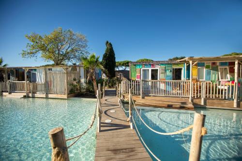 a swimming pool with a hammock in front of houses at Camping La Clape Village in Cap d'Agde