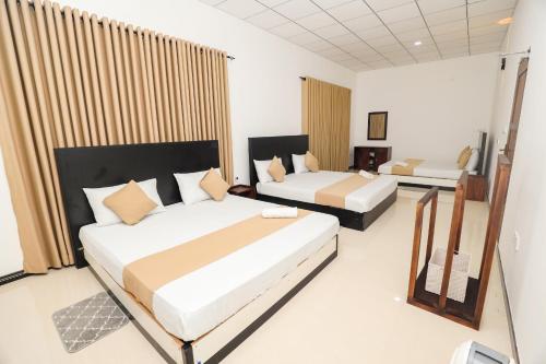 a hotel room with two beds and curtains at Shena resort in Habarana