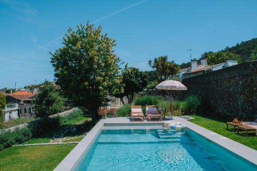 a pool in a backyard with two chairs and an umbrella at Just Like Home - Casa da Tuca in Moledo