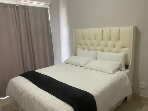 a white bed with a black and white blanket on it at Katima VVIP in Katima Mulilo