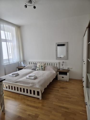 a white bedroom with a large bed and a mirror at Sankt Johannerhof in Ternitz