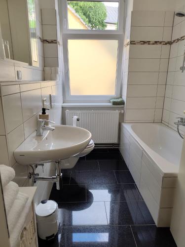 a bathroom with a sink and a tub and a window at Sankt Johannerhof in Ternitz