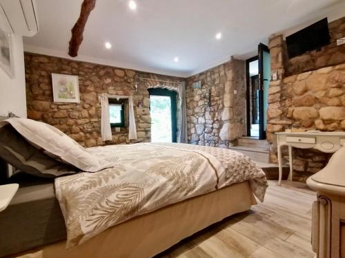 a bedroom with a bed and a stone wall at Mas de lasquiers in Saint-Paul-le-Jeune