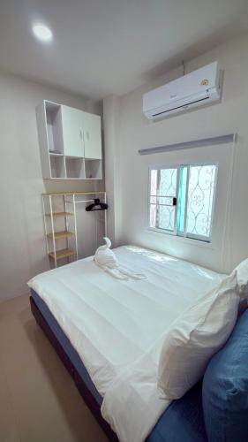a large white bed in a room with a window at The Little House in Chaloklum