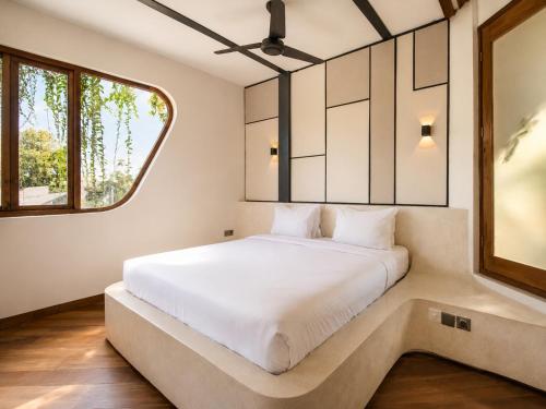 a bedroom with a large white bed with a window at Modern 1-BR Loft with Art Deco Style Shared Pool in Canggu