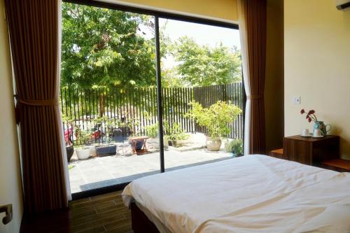 a bedroom with a large window looking out at a patio at Reka Homestay in Thôn Dương Phẩm