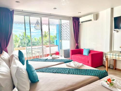 a hotel room with two beds and a red chair at Kelly Hotel Bangsean in Ban Laem Thaen