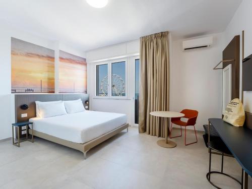 a bedroom with a bed and a desk and a table at B&B HOTEL Pesaro Des Bains in Pesaro