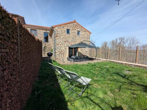a chair sitting in the yard of a stone house at Maison de vacances tout Confort au Calme avec Jardin clos in Saint-Just-près-Brioude