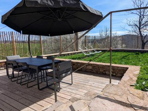 a table and chairs under an umbrella on a patio at Maison de vacances tout Confort au Calme avec Jardin clos in Saint-Just-près-Brioude