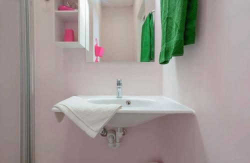 a white sink in a bathroom with green towels at Lungomare Casa Diaz in Cagliari