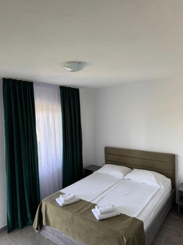 a bedroom with a large bed with green curtains at Casa Osan in Tăşnad