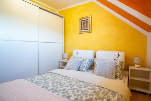 a bedroom with a bed and a yellow wall at Vila Ribič in Železnička Stanica Žejinci
