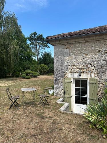 a table and chairs outside of a stone building at Chambre d'hôtes bed and breakfast in La Chapelle-Faucher