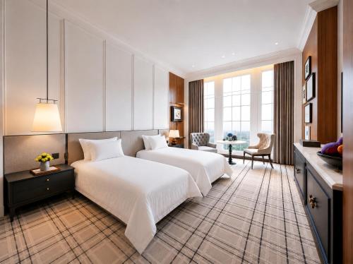 ein Hotelzimmer mit zwei Betten und einem Tisch in der Unterkunft Marqen Hotel in Jakarta