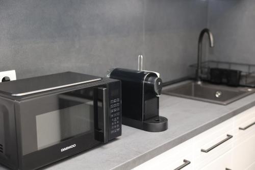 a kitchen counter with a microwave and a sink at Elegant City Home-Free Parking in Timişoara
