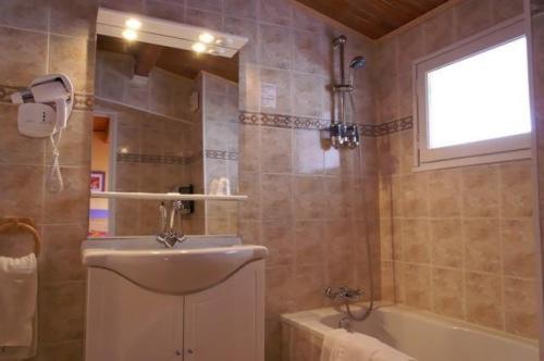 a bathroom with a sink and a bath tub at Hôtel Cristol in Briançon