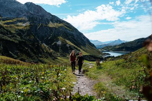 two people walking on a trail in the mountains at ArlbergResort Klösterle in Klösterle
