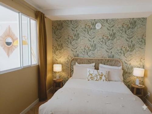 a bedroom with a white bed with a floral wallpaper at Le jardin de Nigelle , En Provence in Mallemoisson
