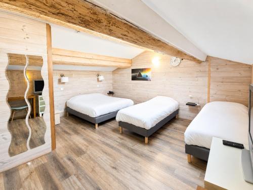 two beds in a room with wooden walls at Le Relais de la Calèche in Le Beausset