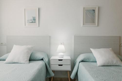 a bedroom with two beds and a lamp on a night stand at Apartamentos Pagán Alejandro in San Javier