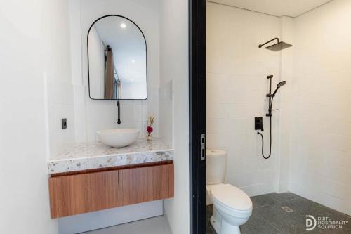 a bathroom with a sink and a toilet and a mirror at Villa didi By sedana cottage in Pererenan