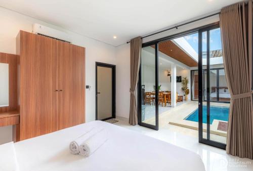 a bedroom with a bed and a swimming pool at Villa didi By sedana cottage in Pererenan