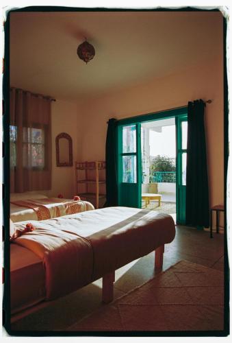 a bedroom with two beds and a sliding glass door at Dar Al-Andalus in Tamraght Ouzdar