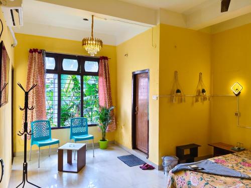 a bedroom with yellow walls and blue chairs and a bed at Mon Aashray Stay in Guwahati