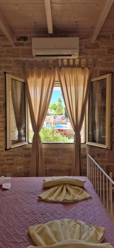 a bedroom with a bed and a window with curtains at Villa Efthalia in Pitsidia