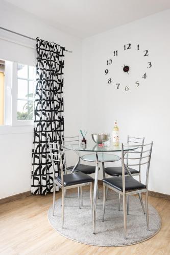a glass table with chairs and a clock on a wall at Maoli A Central Studio Icod de los Vinos in Icod de los Vinos