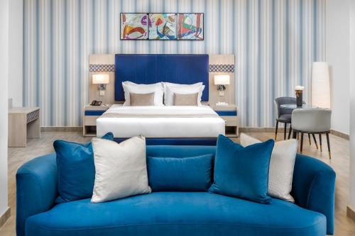a hotel room with a bed and a blue couch at Durrat Balensia Hotel - فندق درة بلنسية in Medina