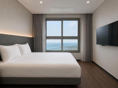 a hotel room with a bed and a flat screen tv at Sky Stay in Incheon