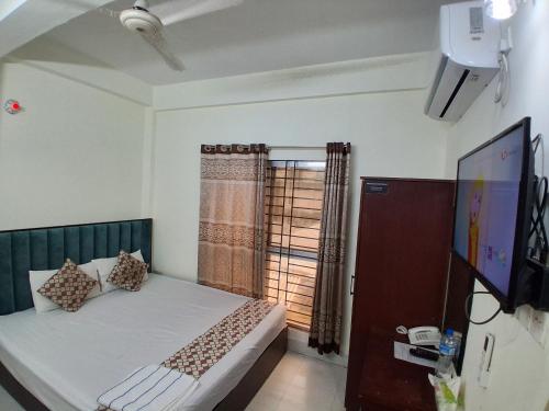 a bedroom with a bed and a tv and a window at Hotel Grand Shah Kamal in Sylhet
