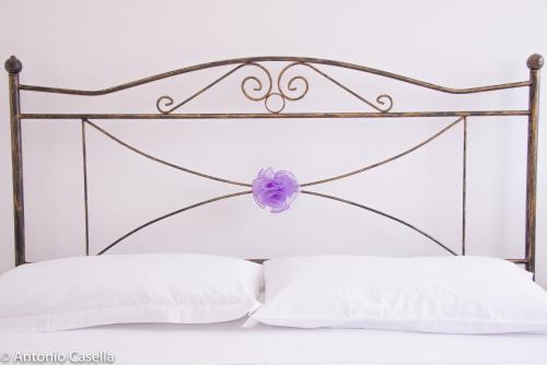 un lit blanc avec une tête de lit en métal et une fleur violette dans l'établissement Appartamento Aurora, à Praia a Mare
