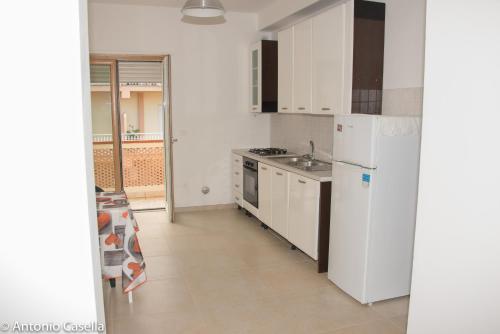 La cuisine est équipée d'un réfrigérateur blanc et d'un évier. dans l'établissement Appartamento Aurora, à Praia a Mare