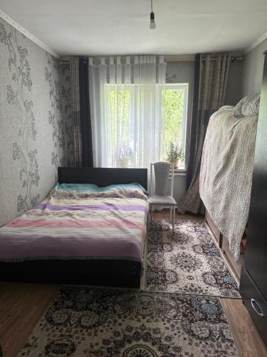 a bedroom with a bed and a window at Дом in Bishkek