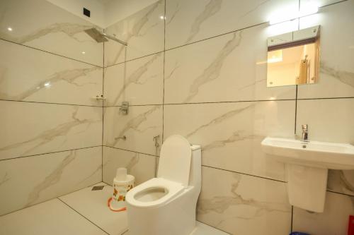 a white bathroom with a toilet and a sink at Rivendell resort Munnar in Munnar
