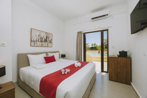 a bedroom with a large white bed with a red blanket at Casa Di Notos Beach Hotel - Georgioupolis in Georgioupolis