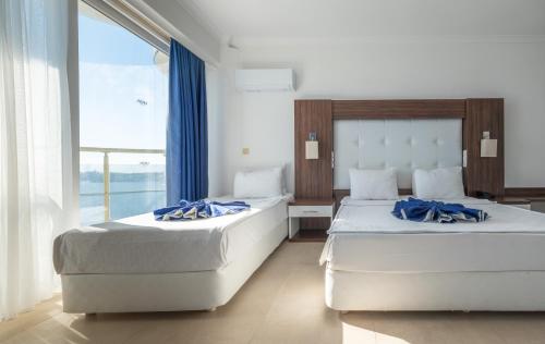 two beds in a hotel room with a large window at Arora Hotel in Kuşadası