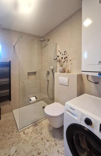 a bathroom with a shower and a toilet and a washing machine at Apartment Oliva Rab in Kampor