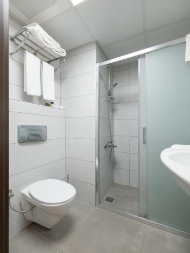 a bathroom with a shower and a toilet and a sink at Arora Hotel in Kuşadası