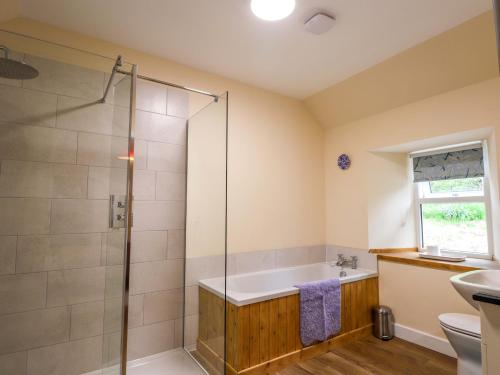 a bathroom with a shower and a tub and a sink at Laundry Cottage in Strathpeffer