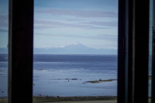 a view of a mountain in the ocean from a window at El Coo Lodge in Queilén